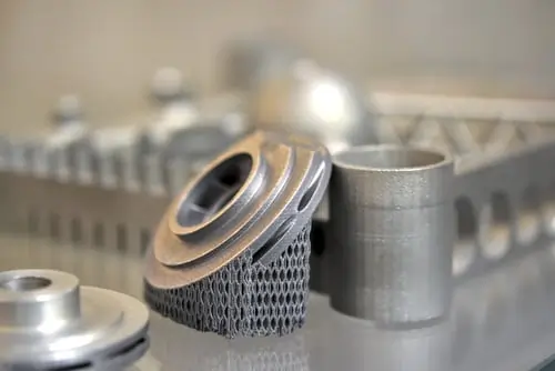 Close-up of various metallic 3D printed parts showcasing intricate designs and textures.