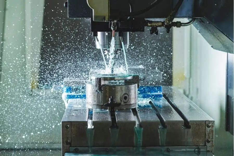 CNC machine in operation with coolant spraying over the workpiece for precision machining