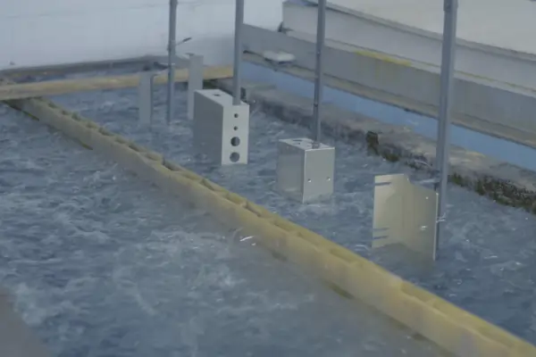 Aluminum sheet metal parts submerged in a liquid bath for an anodizing surface finish treatment.