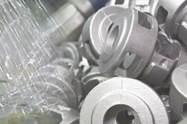 A pile of metal parts with a textured, matte finish from sandblasting or bead blasting.