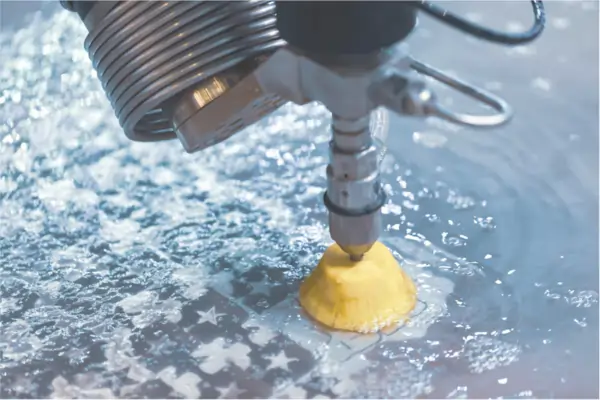 A machine head polishing a metal surface with a yellow abrasive pad under a stream of water.